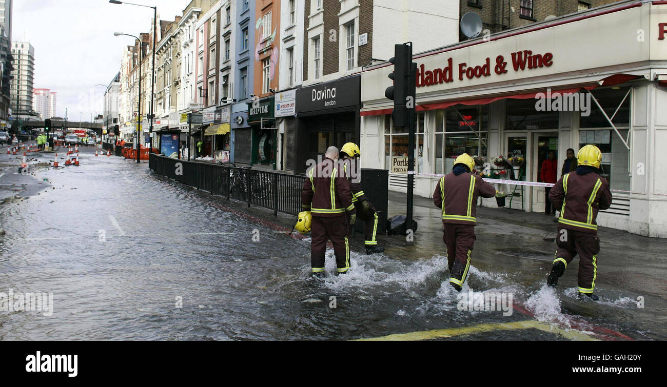 Firemen wade through water after a burst water main in Edgware Road, London. Stock Photo