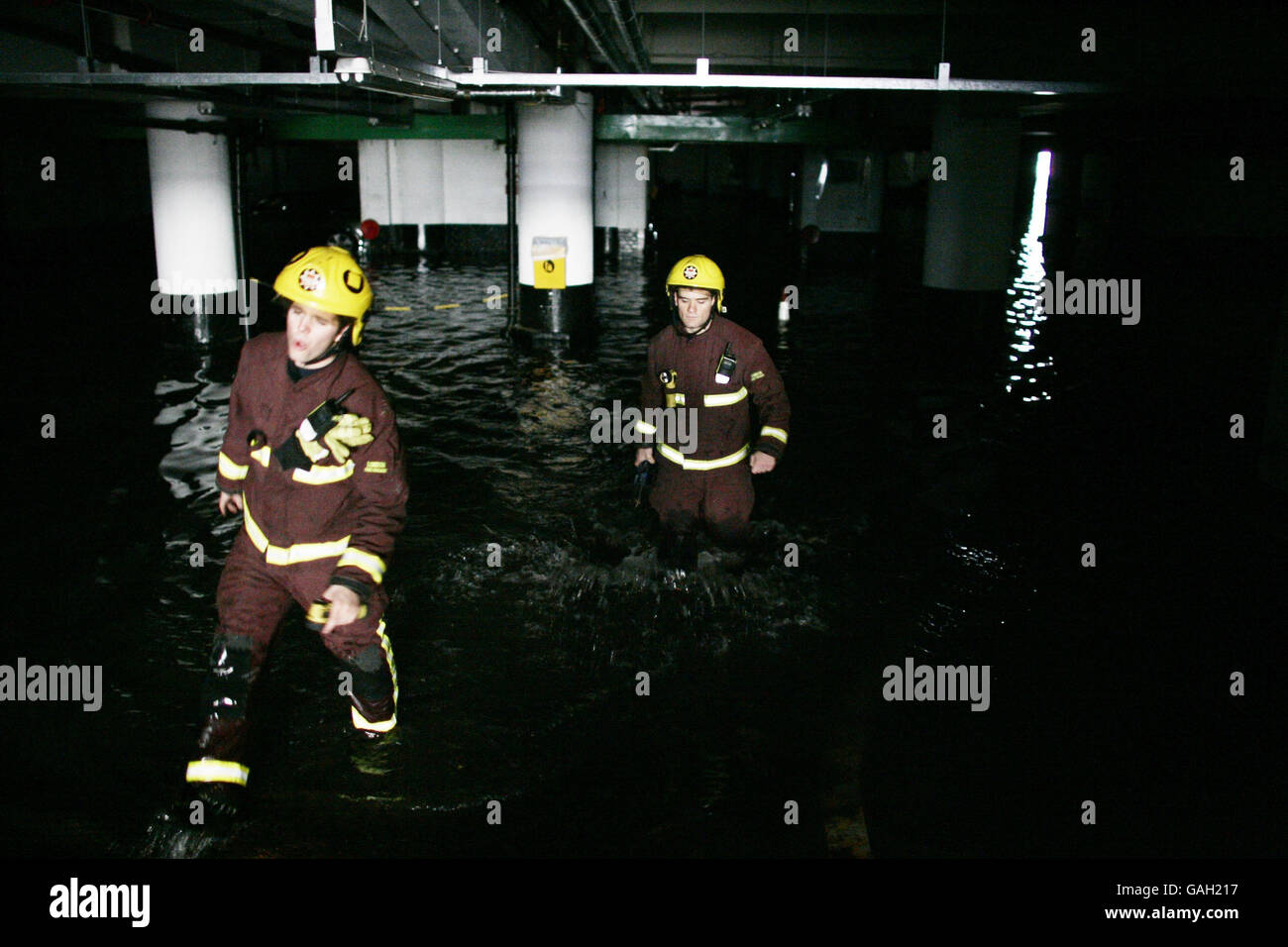 Fireman wade through water in Kendall Street Car Park after a water main burst in Edgware Road, London. Stock Photo