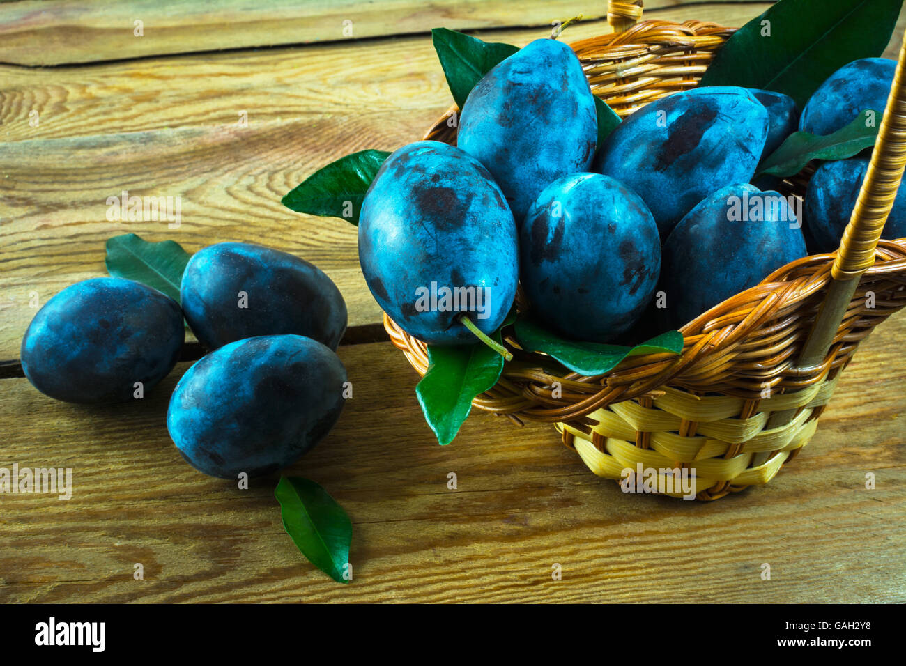 Fruit plum prunes in a basket on a wooden table, close up. Selective focus Stock Photo