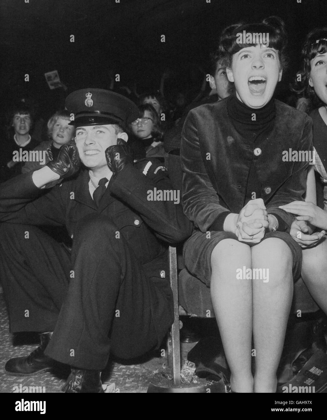 A policeman takes evasive action to block his ears from the screaming fans at the Mersysides group's performance in Manchester Stock Photo