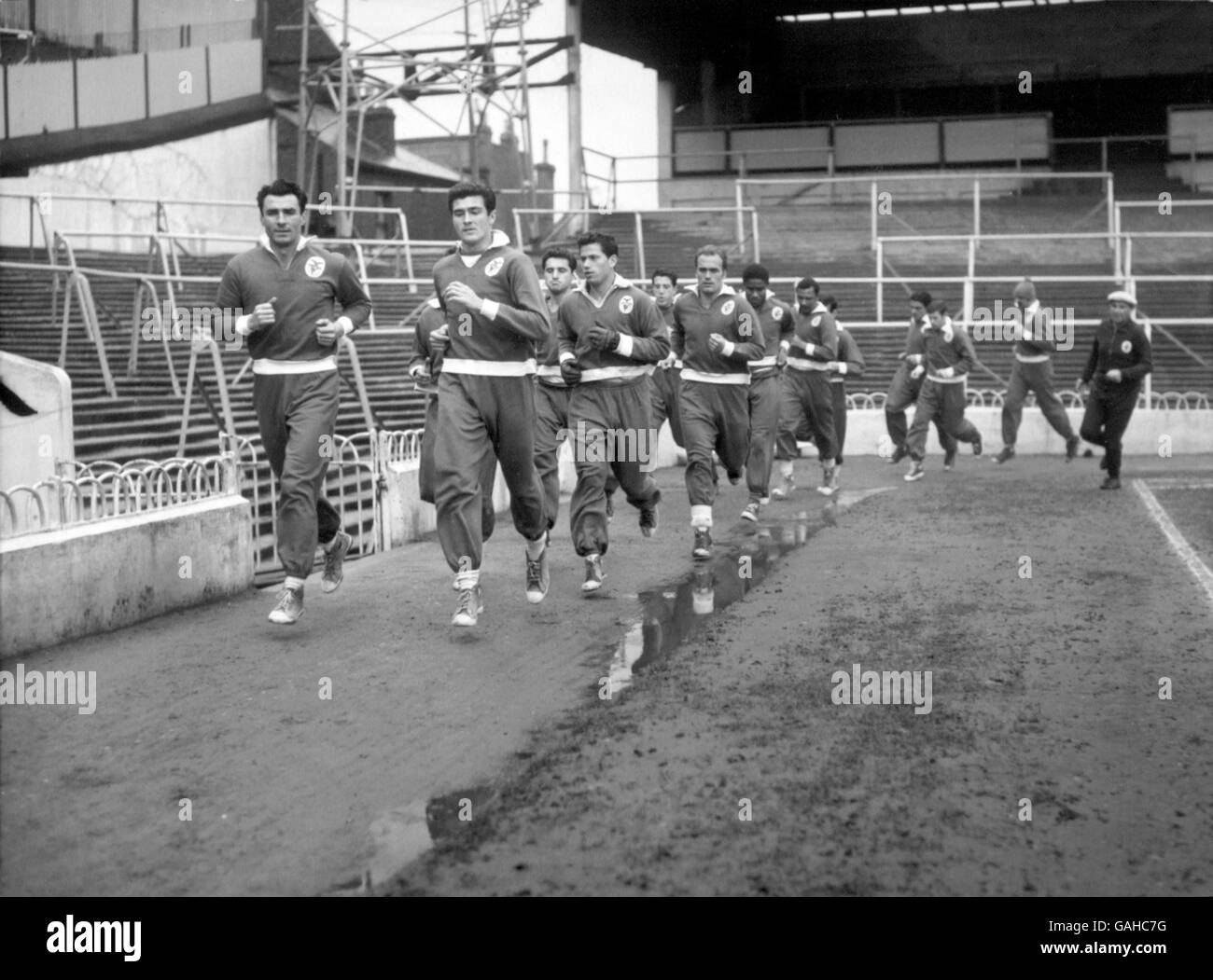 (L-R) Benfica's Alberto da Costa and Jose Aguas lead their teammates around the White Hart Lane track as coach Bela Guttman (far r) struggles to keep up with his young charges Stock Photo