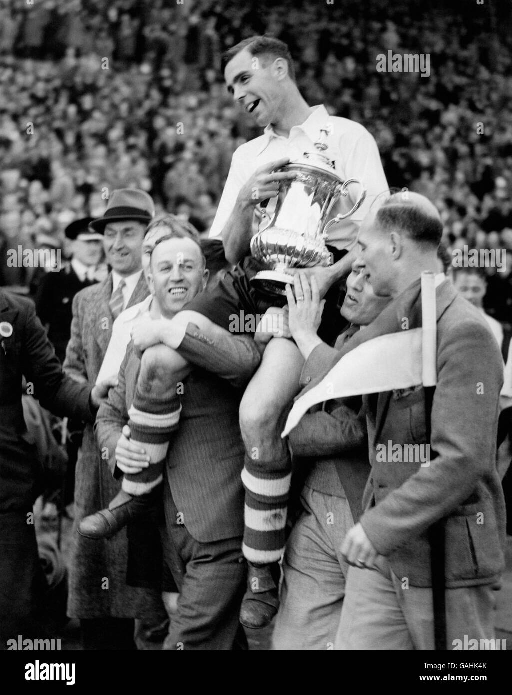 The winning captain, Preston North End's Tom Smith, shows off the FA Cup as he is chaired around the pitch in triumph after the match Stock Photo