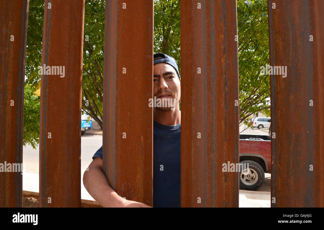 A man in Agua Prieta, Sonora, Mexico, looks through the border wall in to Douglas Arizona, USA. Stock Photo