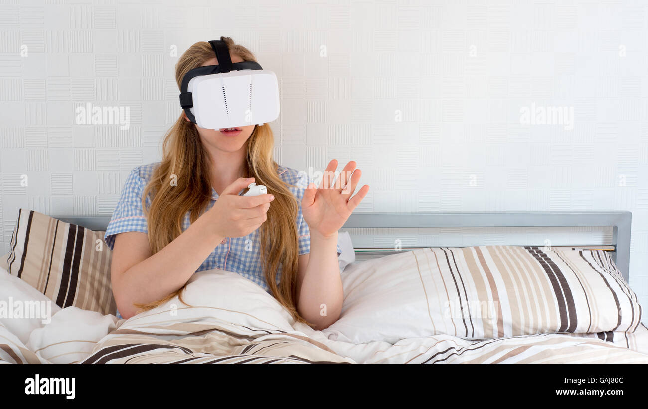 Beautiful woman using VR headset in bed Stock Photo