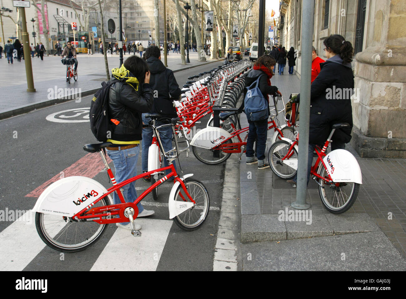 People in Barcelona, Spain, using hired bicycles to get about the city. The new scheme called Bicing enables registered users to take a cycle from any of the 100 automated stations in the Catalan capital and make a journey of up to two hours before returning it to any other station. The bikes' front baskets are locked to a rail which releases when an electronic card is placed against the machine consul. The system is promoted as an extra form of public transport and costs just 0.3 euros per 30 minutes plus an annual charge of 24 euros. Stock Photo