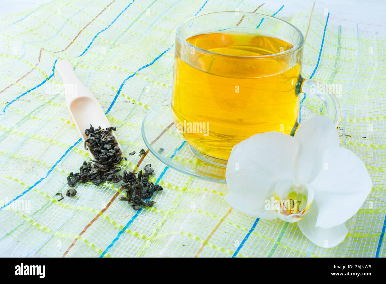 Cup of green tea on green napkin with a white  orchid on a white wooden background. Cup tea. Cap of tea. Tea.  Green tea.  Tea t Stock Photo