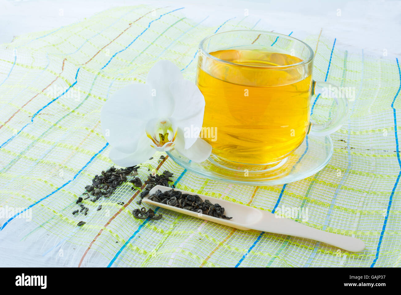 Cup of tea on green napkin with a white orchid on a white wooden background. Cup tea. Cap of tea. Tea.  Green tea.  Tea time. Cu Stock Photo