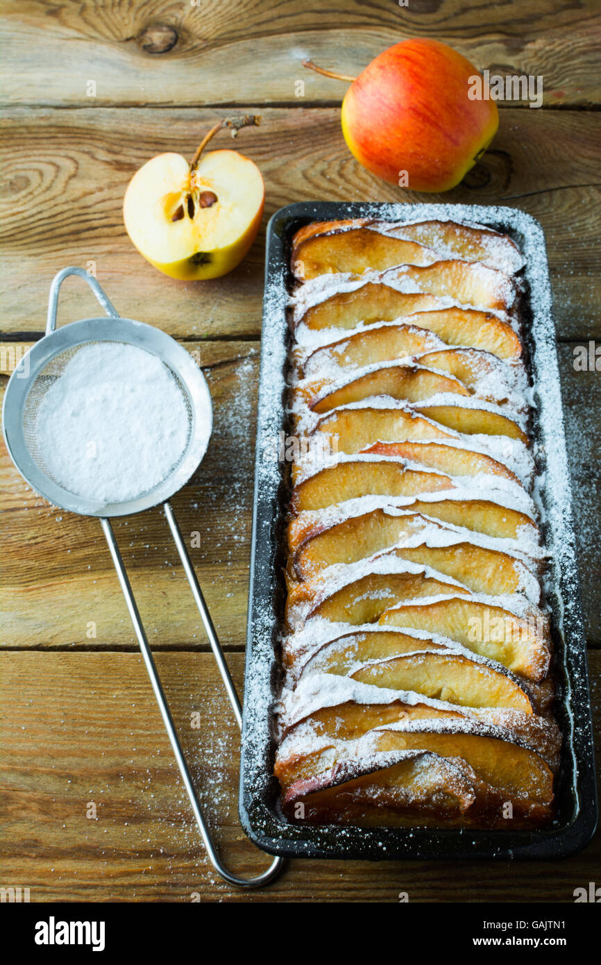 Apple pie, fruit dessert, tart in cake tin and caster sugar. Top view