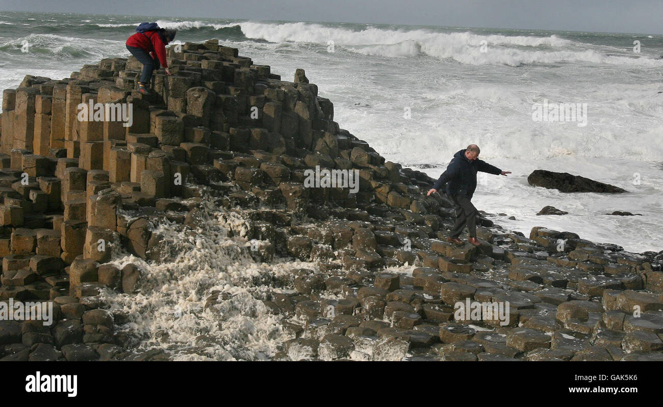 Tourists clamber over stones at the Giants Causeway during as storm batter Northern Ireland. PRESS ASSOCIATION. Picture date: Wednesday March 12 2008. Around 1,000 homes were left without power today after Northern Ireland was battered by overnight winds. Northern Ireland Electricity said the supply has been restored in about 250 households.Counties Tyrone, Fermanagh and Antrim were hardest hit with winds approaching 70mph recorded.But the storms were not as severe as had been feared. See PA story WEATHER Storm. Photo credit should read: Paul Faith/PA Wire Stock Photo