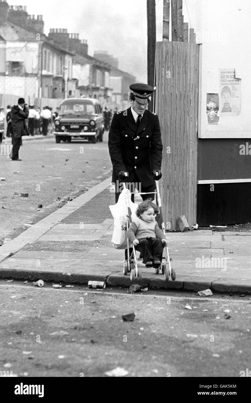 A Police Officer pushes a toddler to safety in Brixton, South London ...