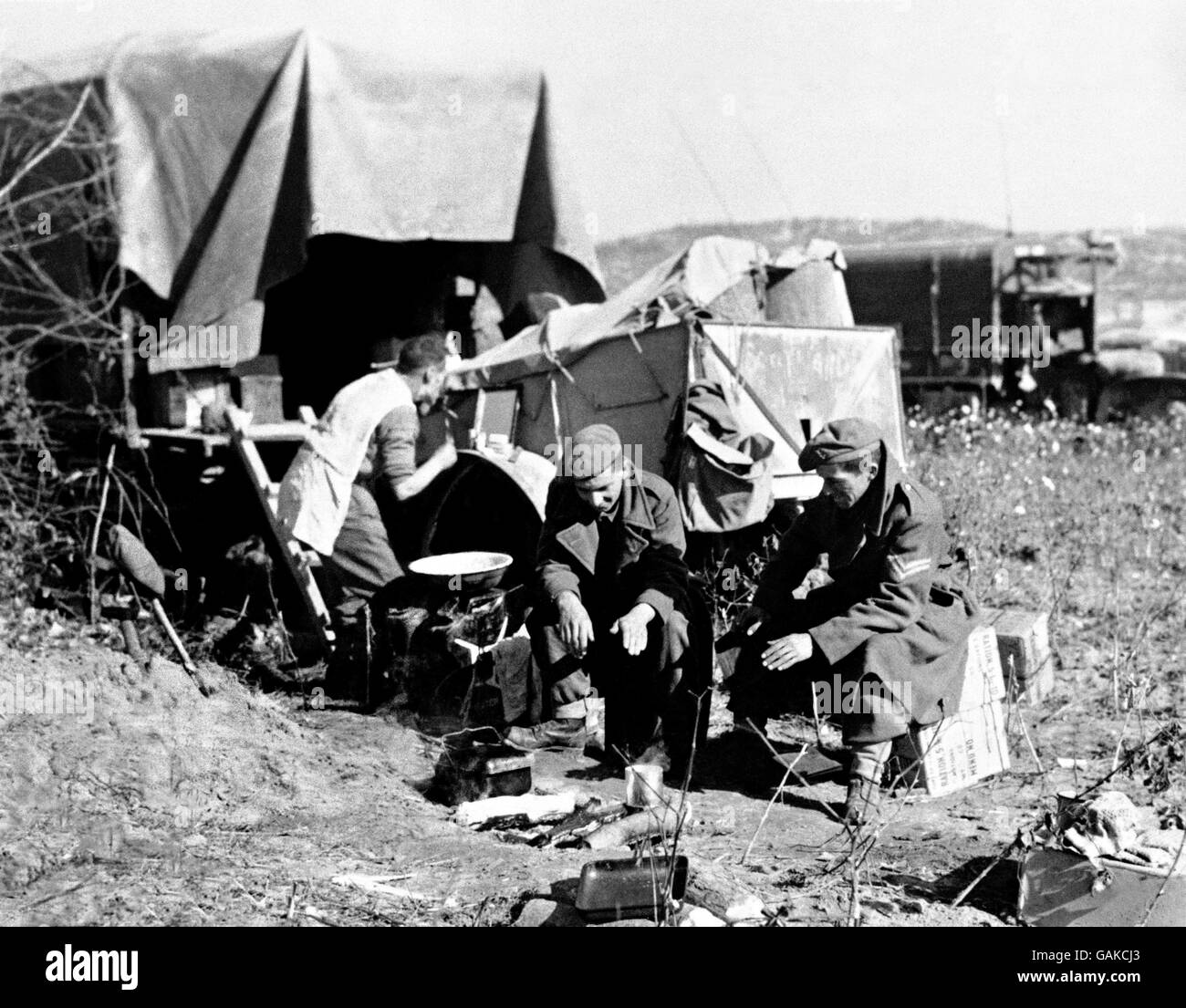 Home away from home for these British soldiers in Korea, the lorry was parked on a piece of flat ground somewhere near the front lines. Private Jones of the Cheltenham (center) and Lance Corporal Jones (right) - members of the corps of the Royal Signals - warm their hands at the fire used to prepare their meal, while Driver Brockman of Canterbury shaves. Stock Photo