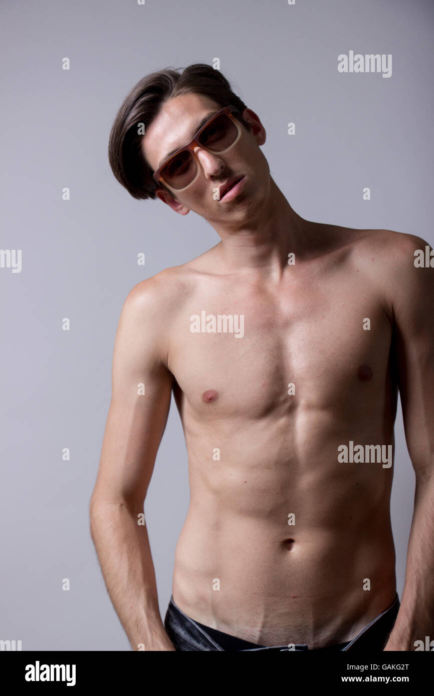 Skinny model showing abs, wearing eyeglasses. Clean background. Stock Photo