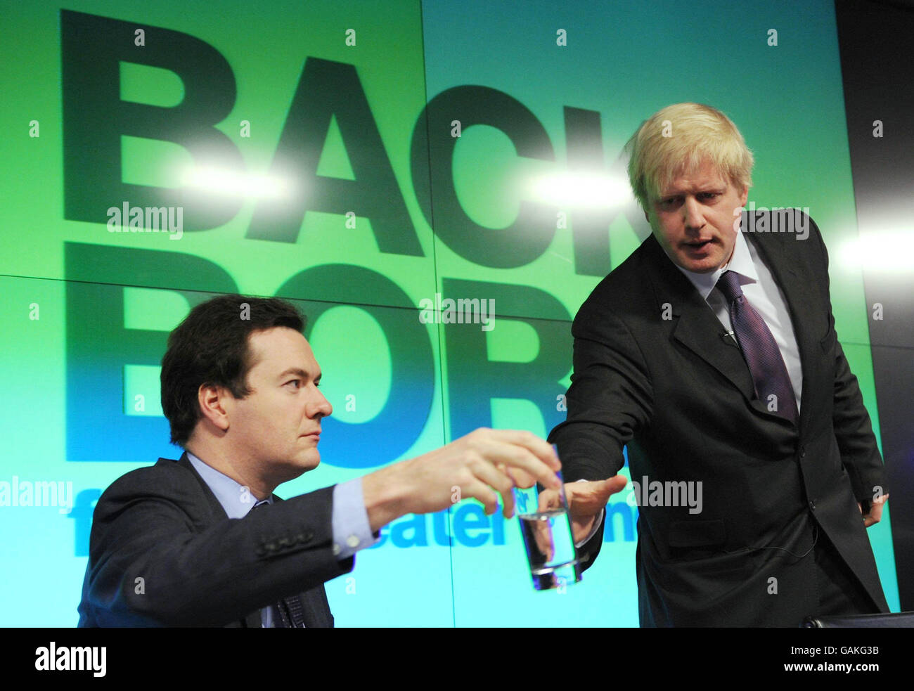 Shadow Chancellor George Osborne hands Conservative candidate for London Mayor Boris Johnson a glass of water as he prepares to make a speech on the economy of London at Bloomberg's offices in the City of London, ahead of this week's budget. Stock Photo