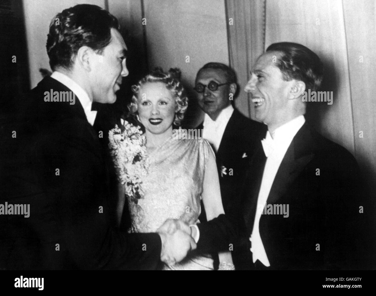 Former World Heavyweight Champion Max Schmeling (l) shakes hands with Nazi Propaganda Minister Joseph Goebbels (r) at a reception thrown by Dr Goebbels in Berlin on the occasion of the German Motor Show. Looking on is Schmeling's actress wife, Anny Ondra (c) Stock Photo