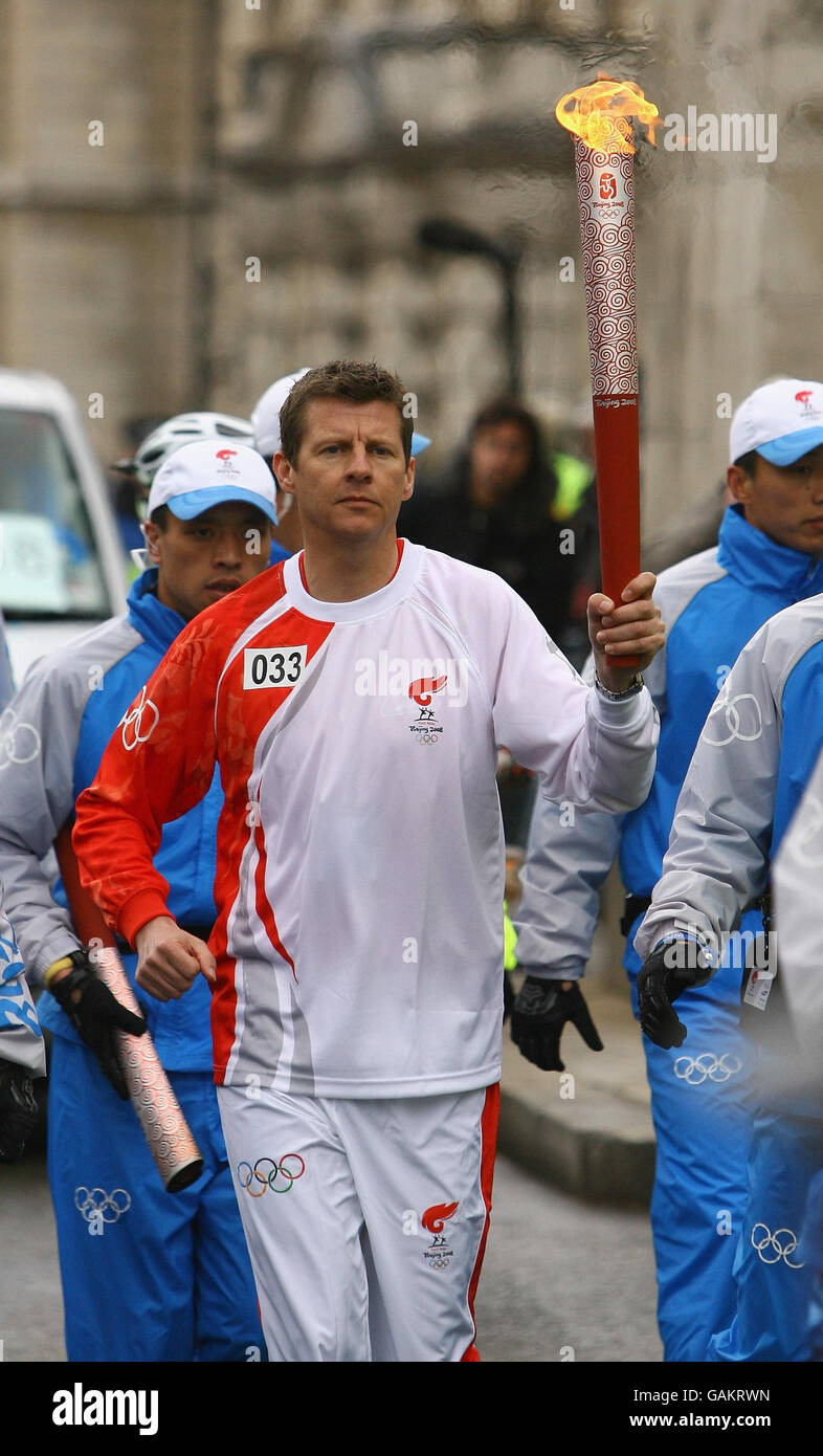 Athlete Steve Cram carries the Olmypic torch during its relay journey across London on its way to the lighting of the Olympic cauldron at the O2 Arena in Greenwich. Stock Photo