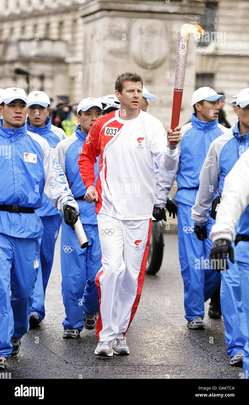 Athlete Steve Cram carries the torch from Trafalger Square during the Beijing Olympics torch relay in London. Stock Photo