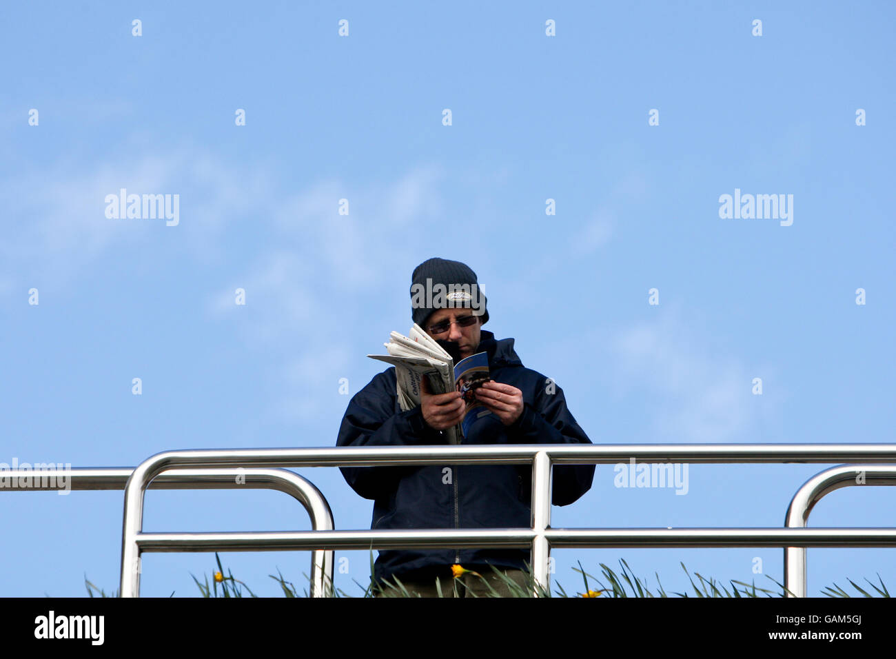 Horse Racing - Cheltenham Festival - Day One - Cheltenham Racecourse. A Punter reads the programme prior to the days racing Stock Photo