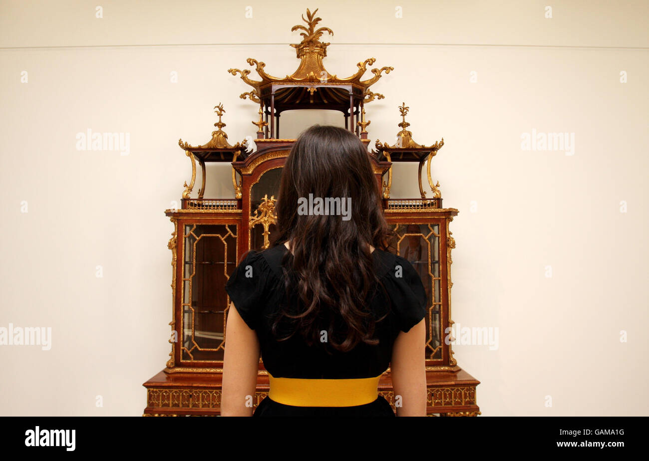 A Christie's employee admires The Kenure Cabinet by Thomas Chippendale, which is to be auctioned at Christie's on the 18th June. Stock Photo