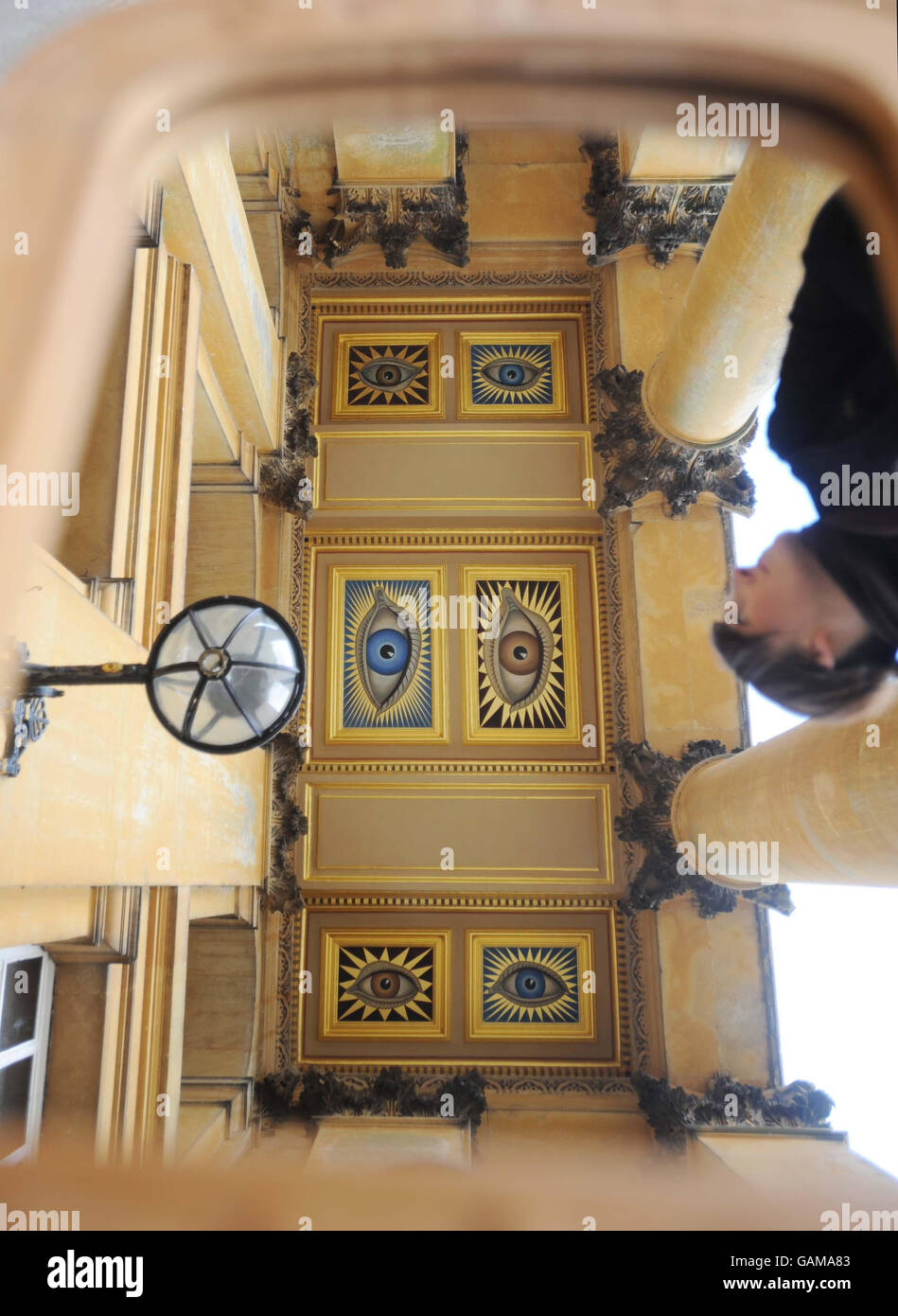 The restored painted eyes above the main entrance to Blenheim Palace,Woodstock, Oxfordshire are viewed by a visitor with their image being reflected in a mirror. Stock Photo