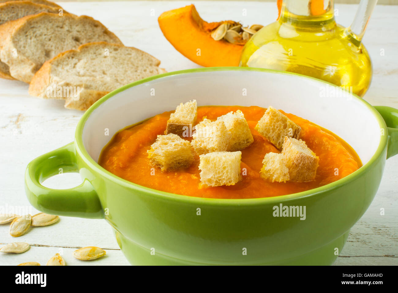 Creamy pumpkin squash vegetable soup with croutons in a green bowl and