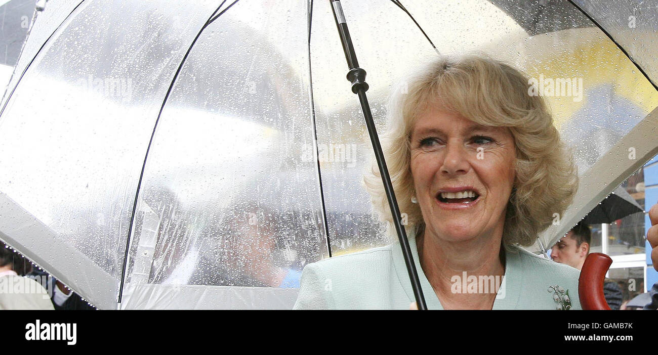 The Duchess of Cornwall gets caught in heavy rainfall as she and the