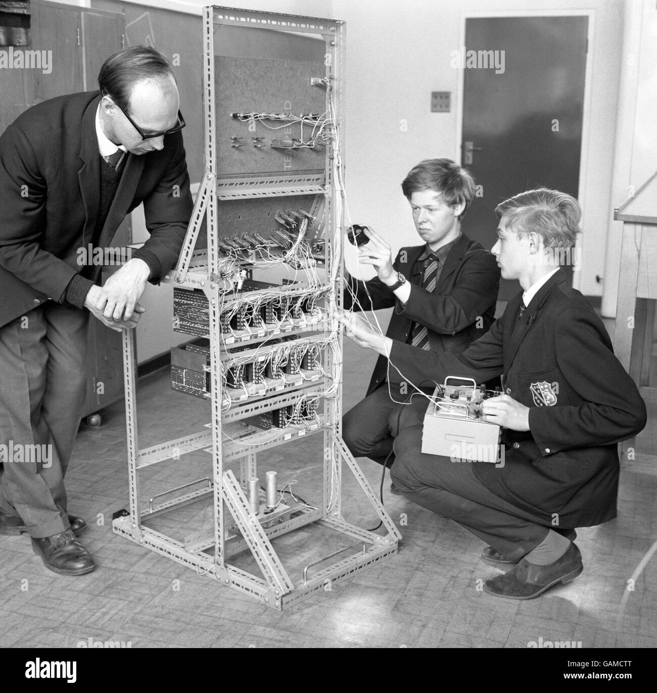 The 'Robot' teacher, a five-feet tall computer built by the sixth form boys at Chesterfield Grammar School in Derbyshire, was developed to give mathematics lessons. It was made from cheap parts from shops selling war disposal stock. Mr A. E. Yorke, the physics and chemistry teacher, introduced the computer 'Bardic' to two of his class. Stock Photo