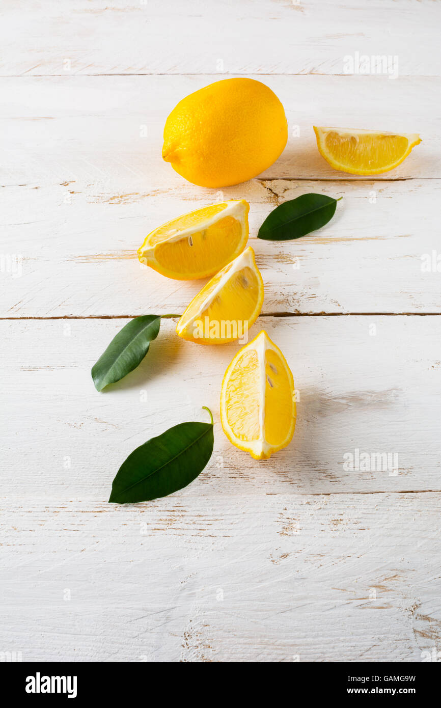 Juicy lemons with leaves on a white wooden background, vertical. Lemon slices. Lemon. Lemons. Citrus. Fruit. Fruits. Fresh Lemon Stock Photo