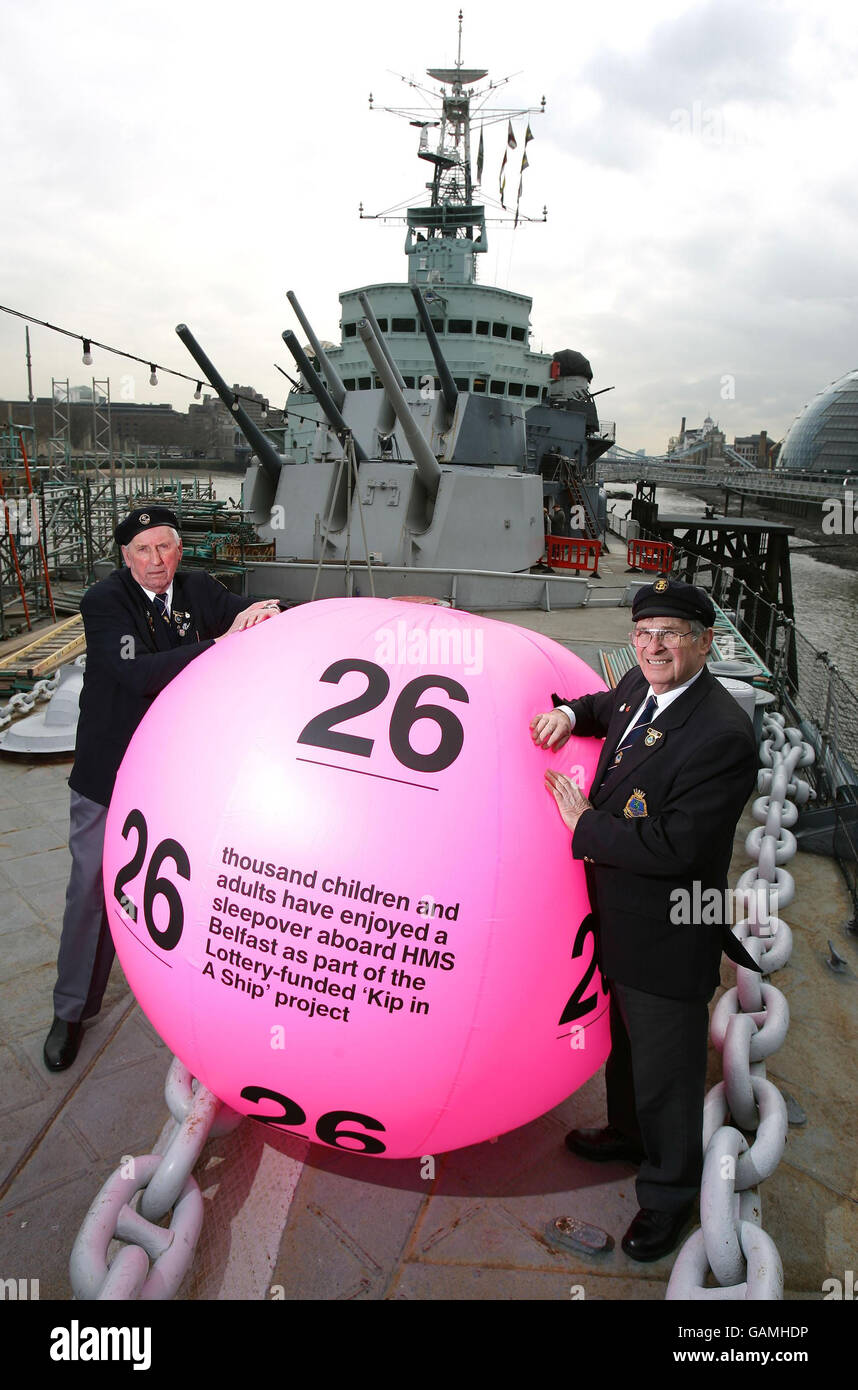 Korean war veterans Bob Blackwell, 78, left and Ted Hill, also in his 70s, welcome a giant National Lottery ball aboard their former vessel, HMS Belfast, on the River Thames, London. Stock Photo