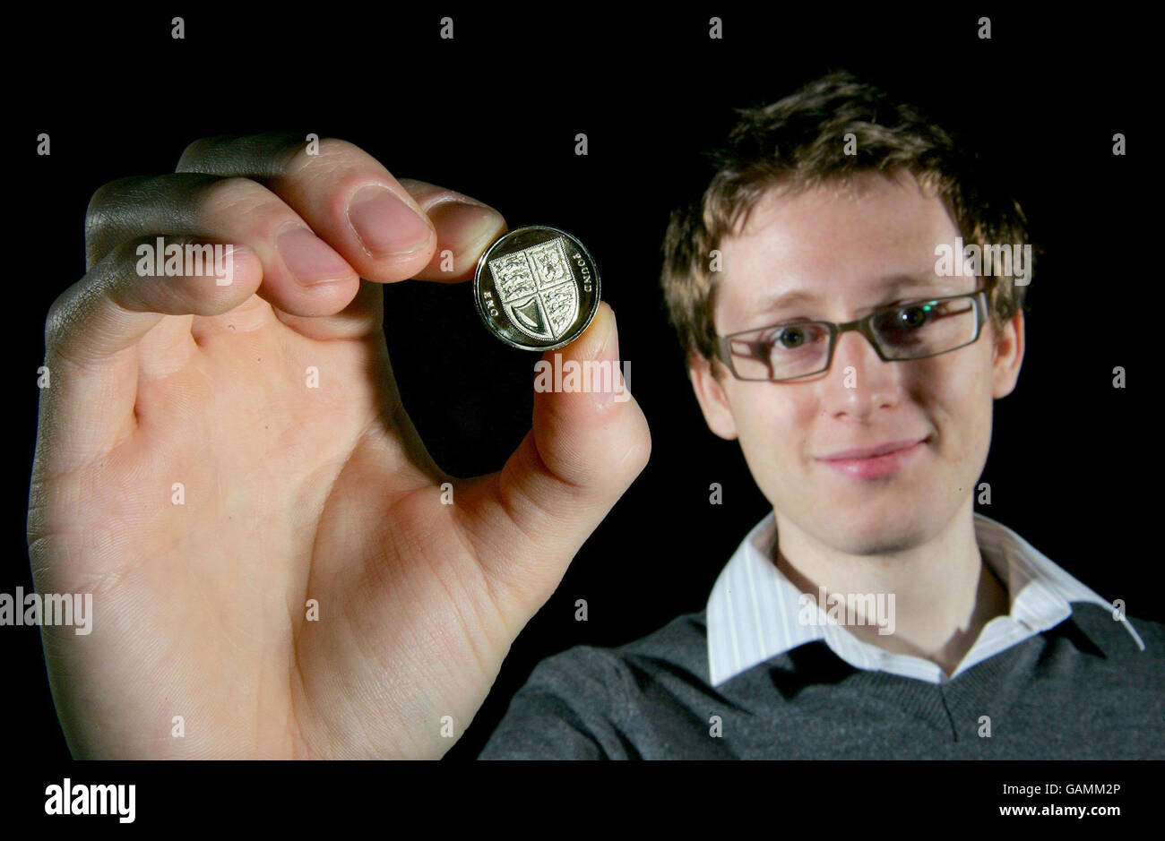 Matthew Dent, 26, a graphic designer from Bangor, North Wales, holds up a 1 coin with the new design as the Royal Mint unveiled their innovative new designs to feature on the reverse of seven of the United Kingdom's coins. Stock Photo
