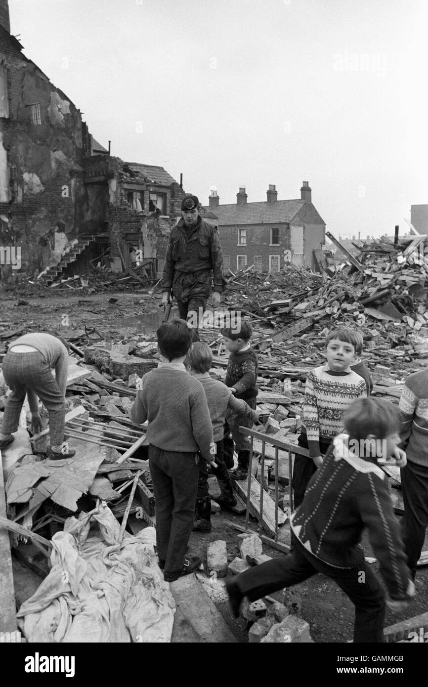 Children remove a baby's cot from the debris of McGurk's bar in North Queen Street, Belfast