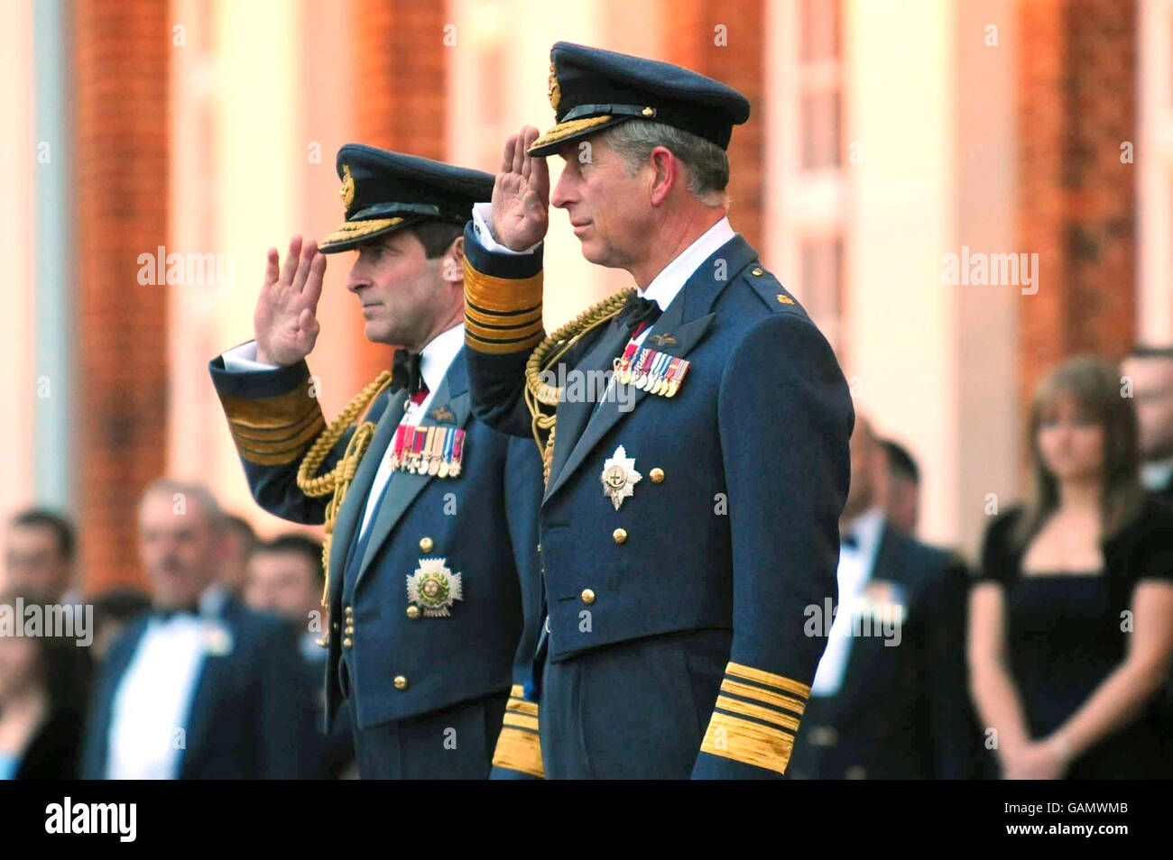 The Prince of Wales, right and Chief of the Air Staff, Air Chief Marshal Sir Glenn Torpy, left, salute during a Sunset Ceremony at RAF Cranwell in Lincolnshire as part of the RAF's 90th anniversary celebrations. Stock Photo
