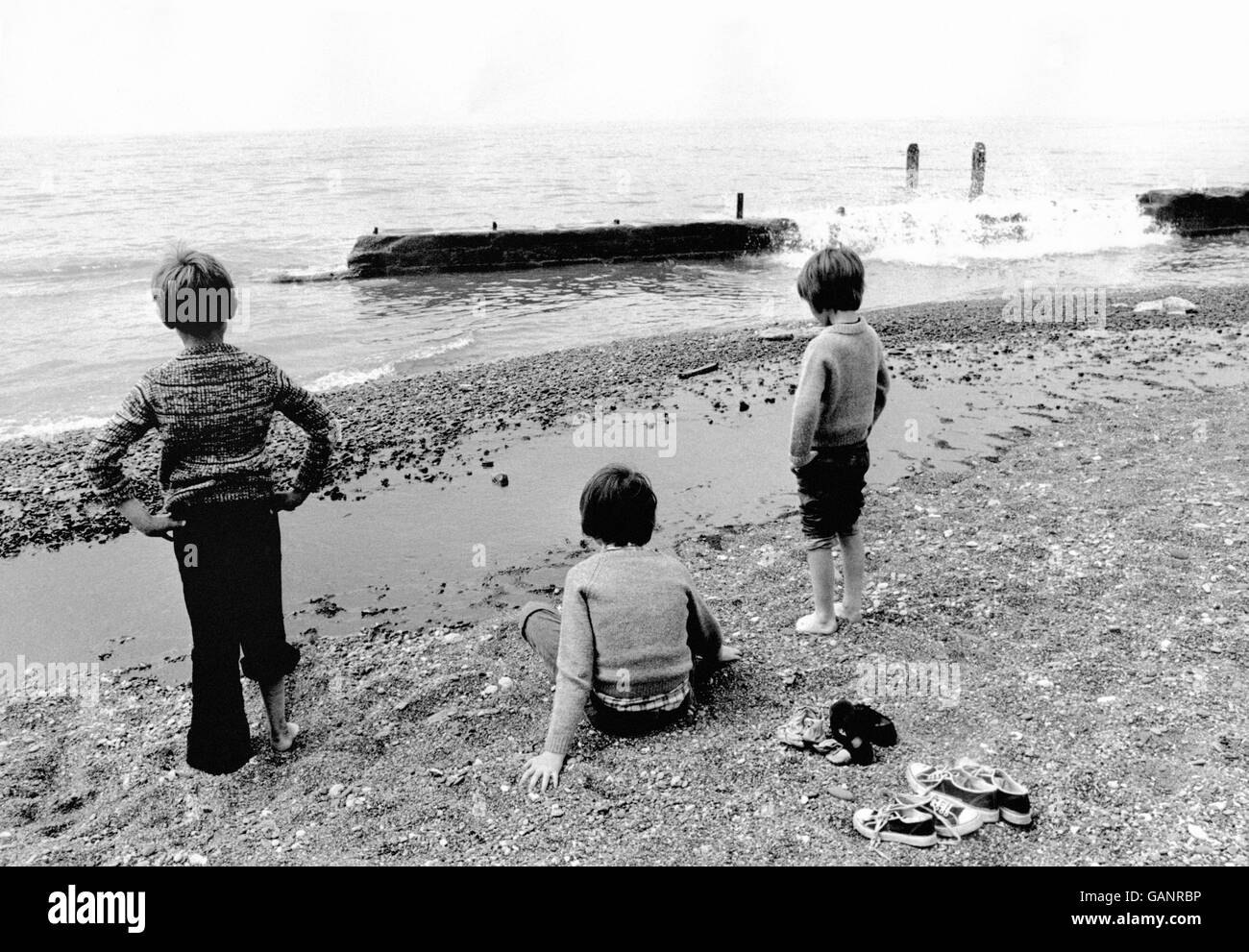 Local youngsters look dejected at the three mile long oil slick that keeps them from the sea at Kilnsea Stock Photo