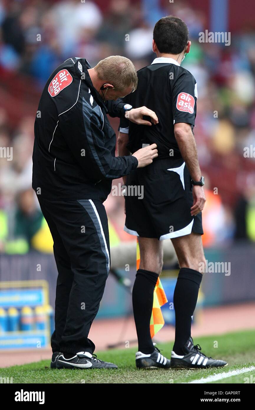 The fourth official reconnects the assistant referee's headset to it's ...