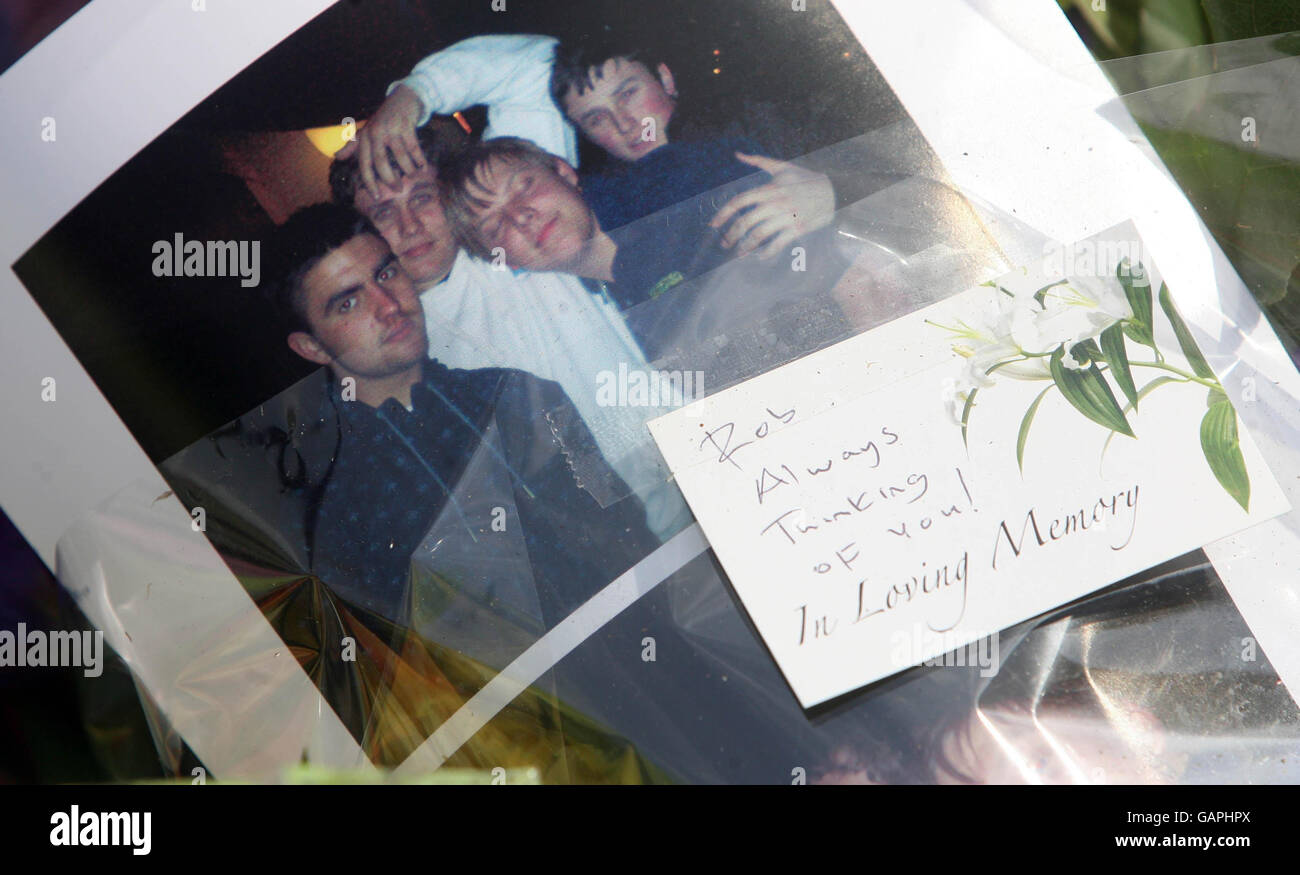 Flowers bearing a photograph of Robert Knox (second left), with unidentified people, placed at the scene in Sidcup, Kent, where he was killed early today. Stock Photo