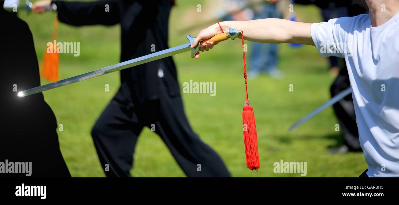 Tai Chi martial arts athlete expert makes motions with sharp sword Stock Photo