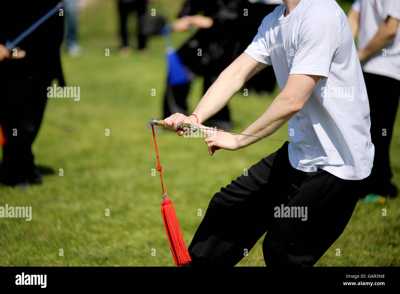 Tai Chi martial arts athlete expert makes motions with sword Stock Photo