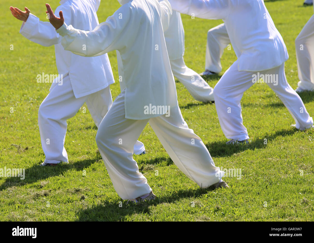 People fans of martial arts with shiny white silk dress during the concentration exercises and relaxation in the large park Stock Photo