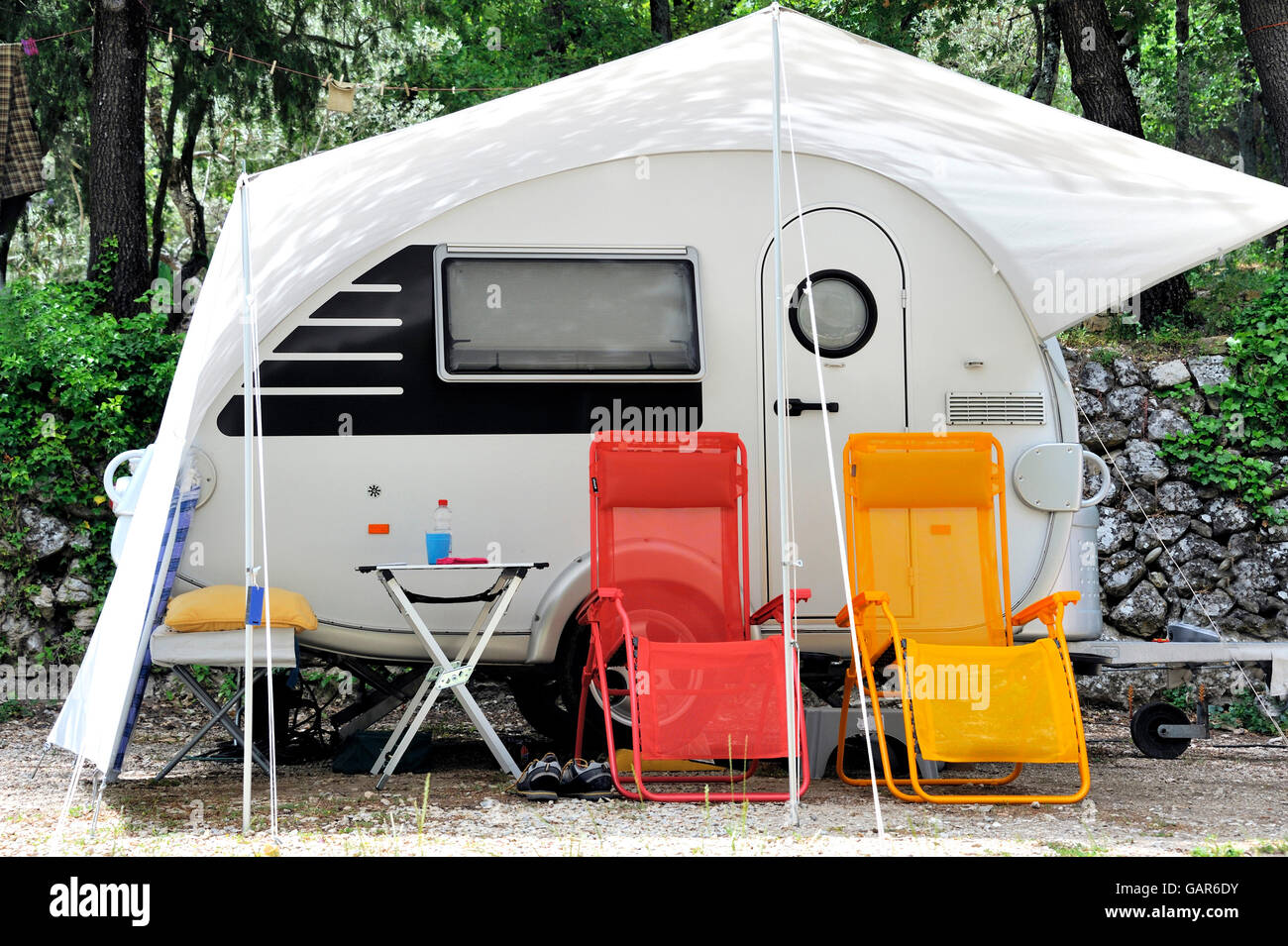 Modern caravan with in front two colored camping chairs Stock