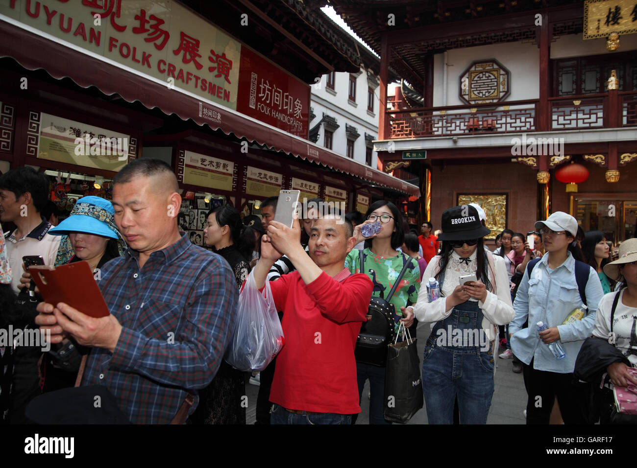 Many tourists, walk and roam in the historical Yuyuan quarter some use smartphones to photograph and take a selfie. Shanghai. Stock Photo
