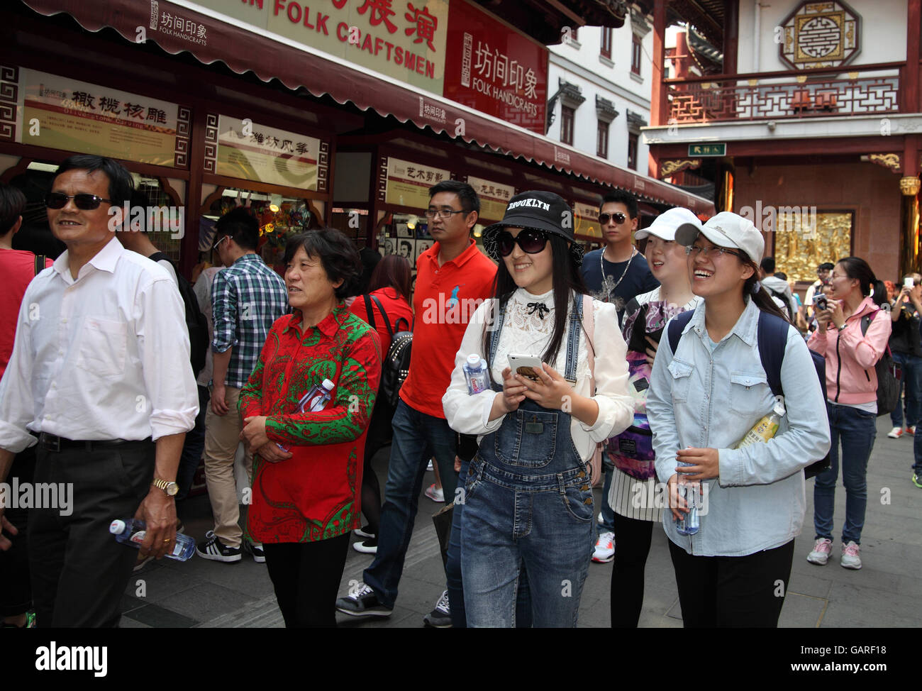 Lots of Chinese tourists, men and women, some smiling, roam around the historical Yuyuan quarter, a popular tourist attraction. Shanghai, China. 30 Stock Photo