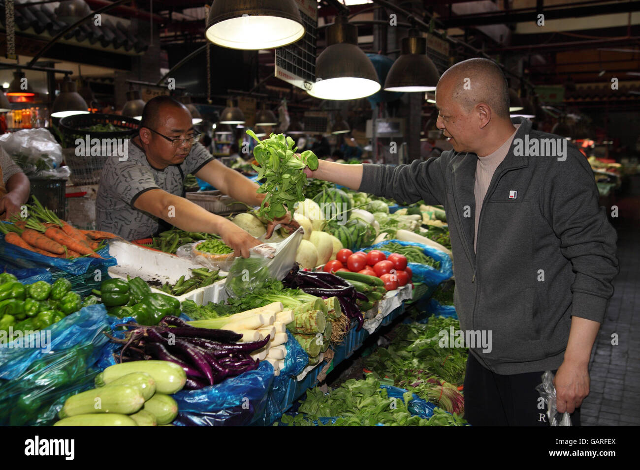 A colorful vegetable and fruit market in the Tianzifang area, the Former French Quarter, here a man buys lettuce. Shanghai. Stock Photo