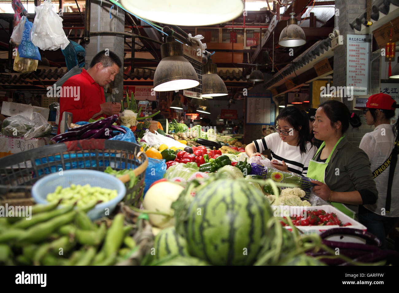 Two women buy vegetables in the colorful vegetable and fruit market in the Tianzifang, the Former French Quarter. Shanghai. Stock Photo