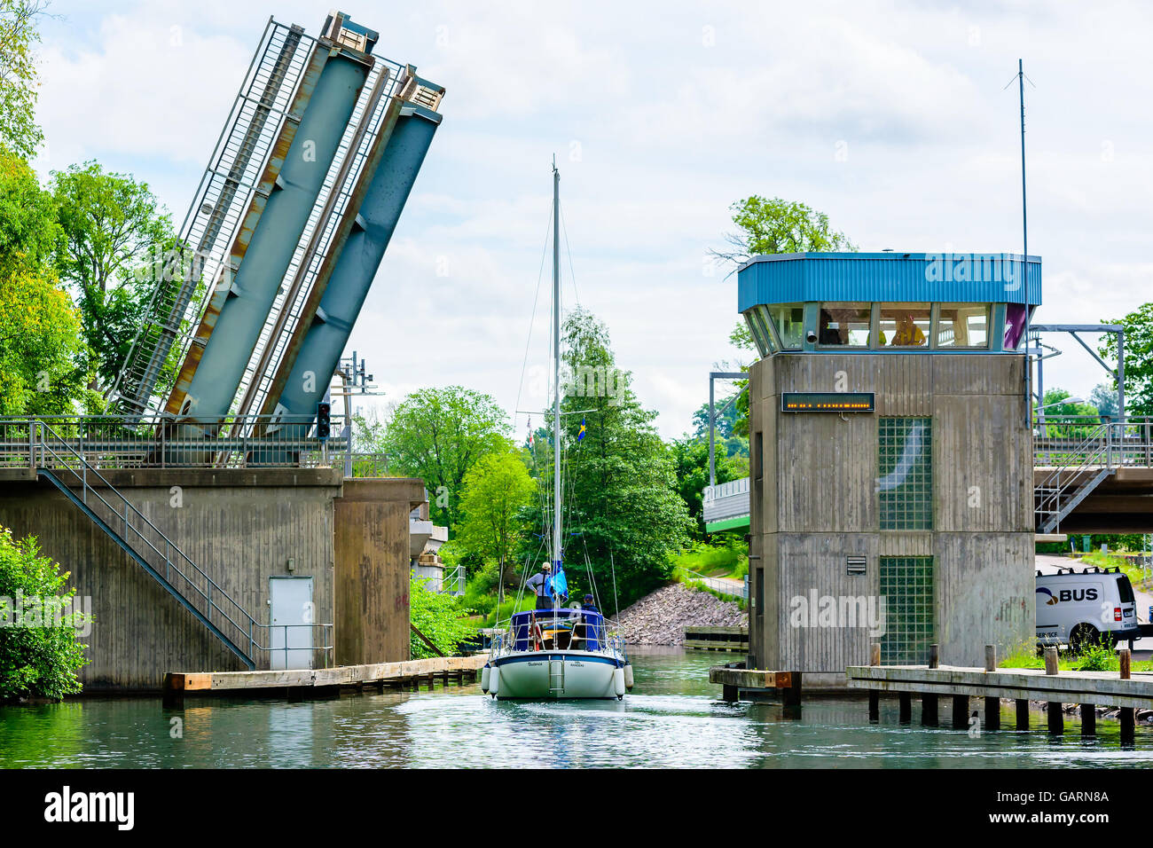 Motala, Sweden - June 21, 2016: Sailboat traveling under a movable bridge. People visible inside the control tower at the side o Stock Photo