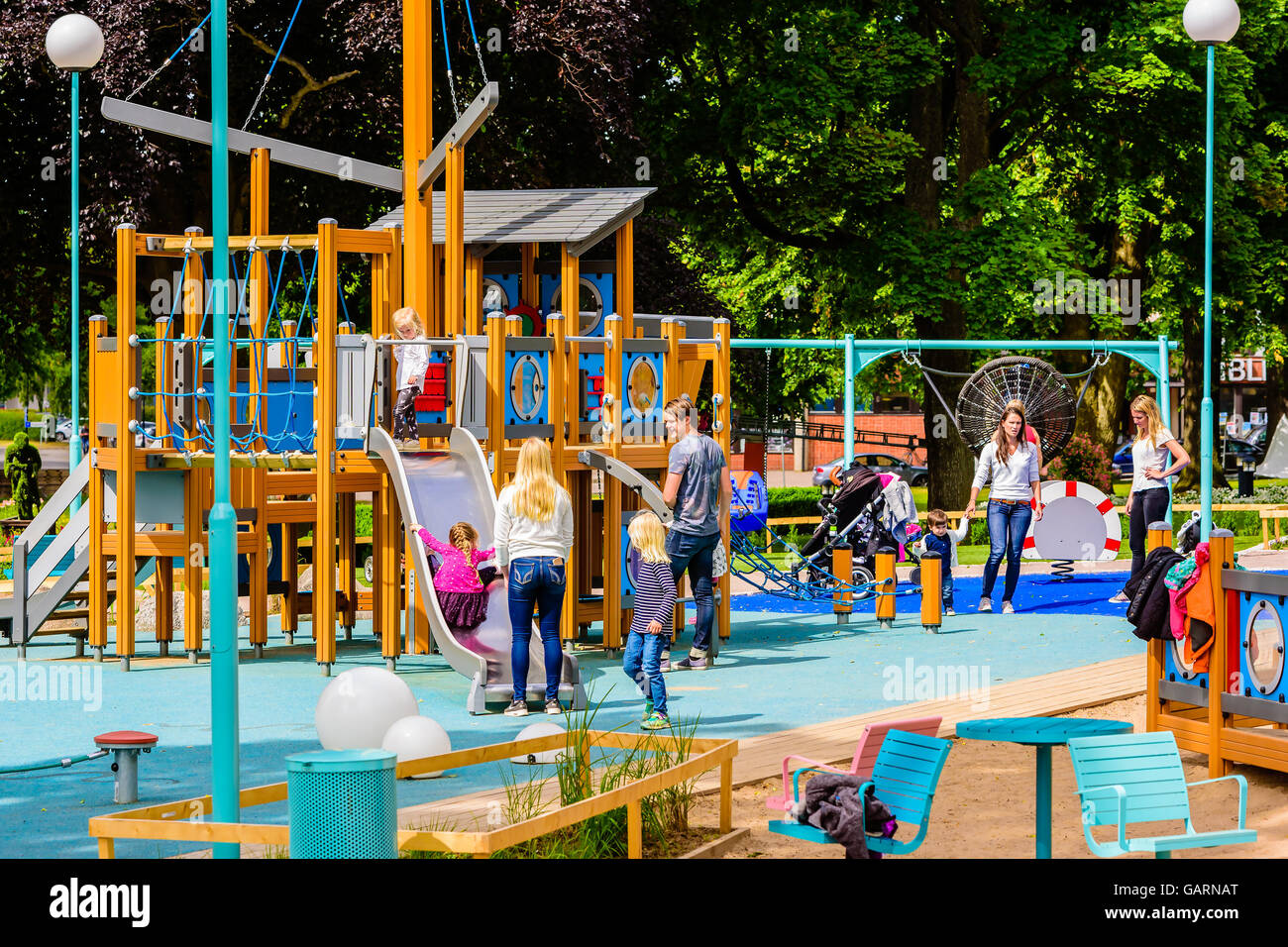 Motala, Sweden - June 21, 2016: Children and adults at a public playground in the city. Real life situation. Stock Photo