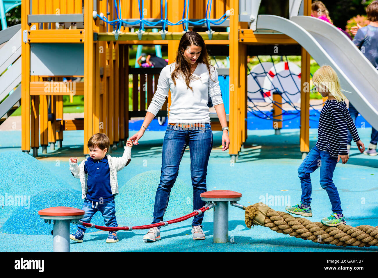 Motala, Sweden - June 21, 2016: Young adult female walking with a young boy at the playground. Possibly mother and son. Girl wal Stock Photo