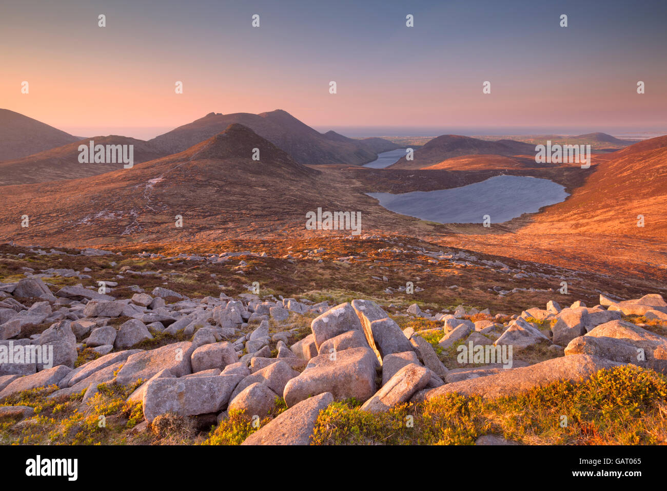 Sunrise over the Mourne Mountains and lakes in Northern Ireland. Photographed from the peak of Slieve Loughshannagh. Stock Photo