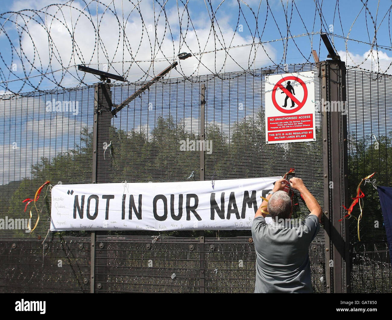 Peace campaigners place banners on the fence at Faslane before trying to form a chain around Faslane nuclear base near Glasgow to highlight the budget for nuclear weapons. Stock Photo