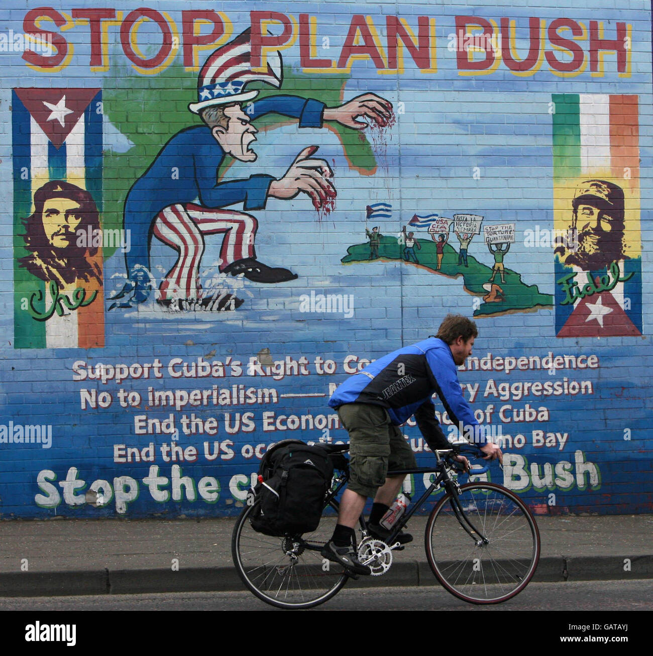 A man cycles past a mural on the Falls Road in West Belfast as ahead of the visit of US President George Bush to the Stormont Castle in Belfast. Stock Photo