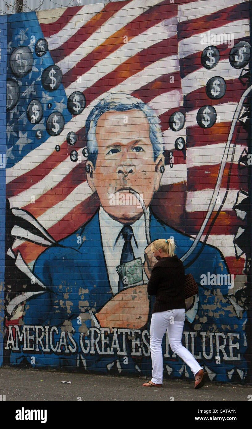 A woman walks past a mural on the Falls Road in West Belfast as ahead of the visit of US President George Bush to the Stormont Castle in Belfast. Stock Photo