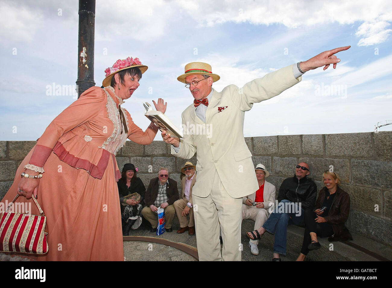 Bloomsday participant Jim Carroll, dressed as Ulysses protagonist Leopold Bloom, gets into the Bloomsday spirit by reading extracts from Joyce's novel to his wife Breda,who is dressed as Molly Bloom, on top of the Joyce Tower in Sandycove, Dublin. Stock Photo